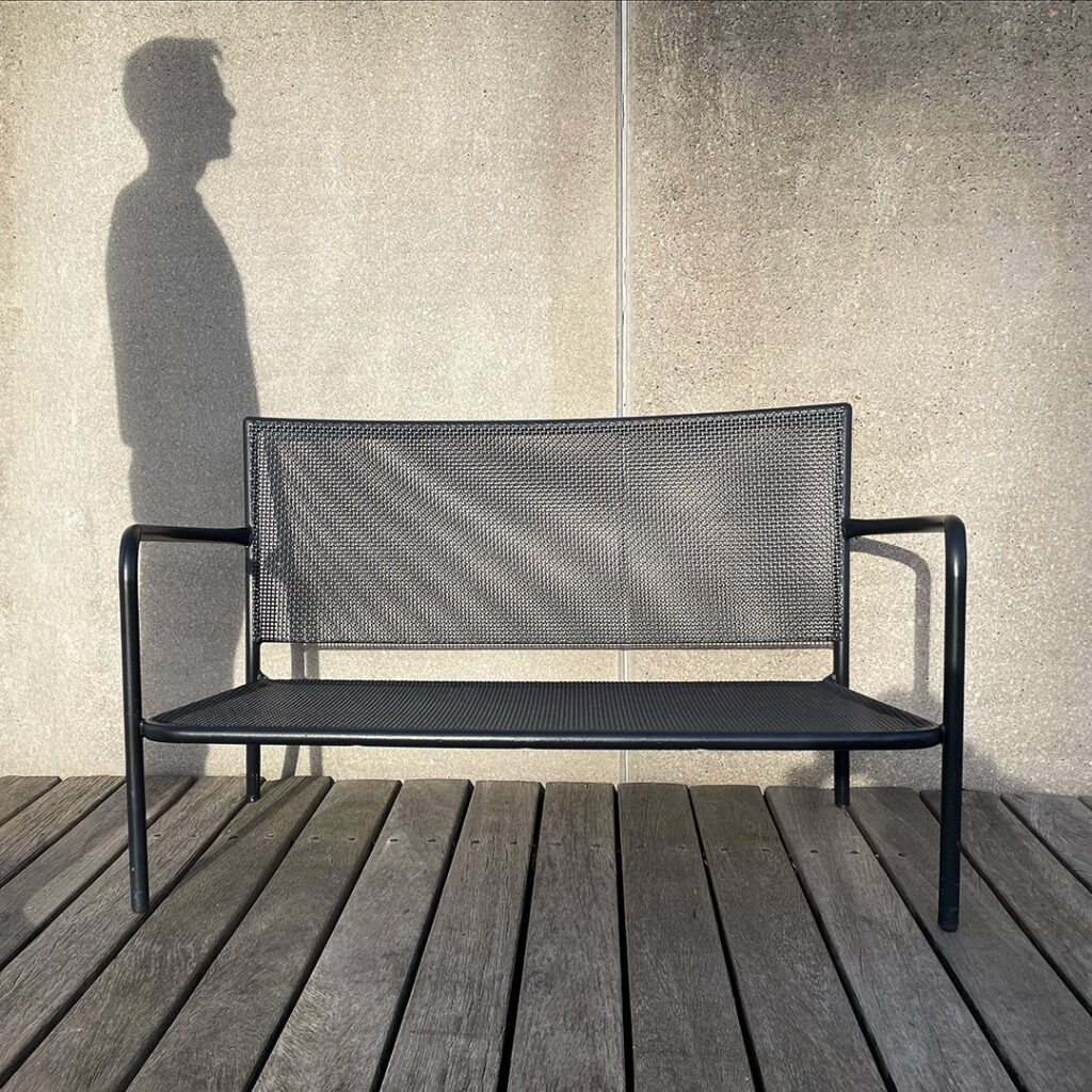 Skyggen af en eksistentiel psykoterapeut, foran en tom bænk.