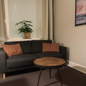 Terapilokale på Østerbro i København, indrettet med sofa, planter, billeder og gardiner.